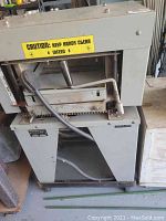 Front view of planer showing infeed table, cutter housing, stand and warning label.