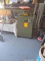 Front view of green rabeting jointer on casters with orange tabletop and control panel