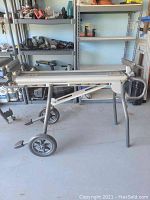 Photo of miter saw stand showing the side view with wheels, foot pedals, and folding design.