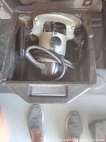 Electric hand mixer with cord inside black plastic carrying case, shown from above.