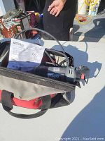 Bosch RotoZip rotary cutting tool with attached power cord inside a soft carrying case along with the instruction manual.