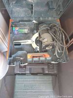 Orange and black carrying case with Bosch handheld wood router inside, power cord wrapped around tool. Case includes small accessories and a box of router bits.