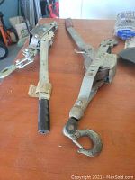 Photo shows two metal trailer hitches with hooks and lever handles on a wooden surface.