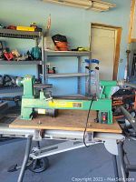 Photo shows the Central Machinery wood lathe placed on a workbench with shelves and other tools in the background.