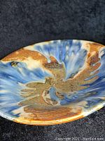 Close-up of the bowl interior showing the glaze swirl in blue, brown, and cream colors with glossy finish.