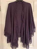 Front view of the deep purple/eggplant shawl with long fringe along edges hanging on a hanger.