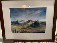 Framed watercolor print showing a mountain landscape with trees, fence, and sky, highlighting the artwork and condition of frame.