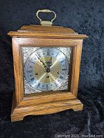 Full view of the wooden case mantel clock with top handle, showing the clock face inside without the glass panel.