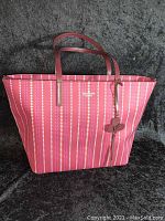 Front view of burgundy and pink heart print tote showing embossed logo and dual handles