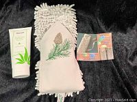 Norwex Everyday Clean Hand Sanitizer tube next to Pine Cone Chenille Hand Towel, towel in white/cream color with green/pine embroidery.