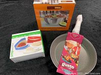 Photo of the three boxed kitchen items: Oggi Prep serving bowl, Gusto non-stick fry pan, and Prepworks Dough Press Set