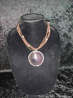 Displayed on black velvet bust showing the full necklace with pendant front and center.
