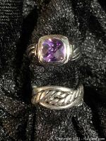 Two sterling silver rings, one with a faceted purple amethyst stone and the other a plain twisted rope design band.