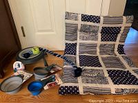 Photo shows handmade quilted patchwork dog bed or crate pad, fleece braided dog toy, and collapsible bowls and food measuring cups arranged on wooden floor.