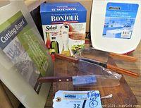 Full lot including cake server, salad chef mixer in box, cutting boards sealed in packaging, and wood butcher block with handles