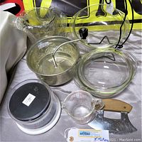 Full view of the lot showing Pyrex glass oven bowls, glass lid, metal food mill, plastic and metal food scale, measuring cup, dough cutter, and banana stand.