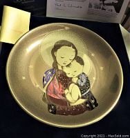 Front view of the plate showing hand-painted image of a woman holding a child with 24K gold accents and rich color details.