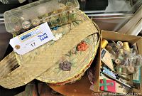 Round woven basket with flowers on lid containing spools of thread, a plastic organizer box, and sewing accessories.