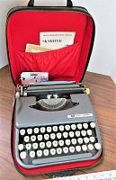 View of vintage Smith-Corona Skyriter typewriter in open red interior zipper case with instruction manual in mesh pocket
