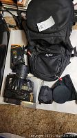 Overview of camera body, lens, bag, books and accessories on carpeted floor