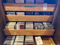 Wooden rack with three pull-out shelves holding assorted CDs in jewel cases