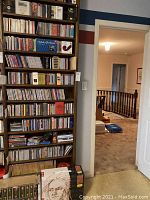 Tall wooden bookshelf filled with rows of CD jewel cases and box sets