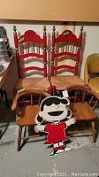 Shows the full lot with two red oak ladderback rush seat chairs, two small wood chairs, and Lucy from Peanuts standup in front.