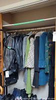 Row of assorted coats and jackets hanging on wooden rod