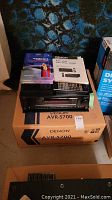 Denon AVR-5700 receiver with original box, manuals, CineoQuest Video 1 CD and remote control shown on top of the box.
