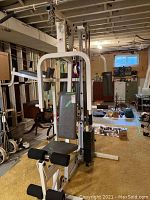 Frontal view of assembled multi-station gym showing seat, backrest, weight stack, and leg developer.