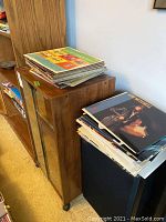 Wood-grain veneer cabinet with glass doors, LP stack on top, speaker next to it
