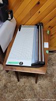 Wooden table top with paper cutter placed on it