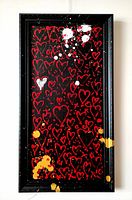 Frontal view of entire framed painting showing repeated red hearts, white and yellow splatters.