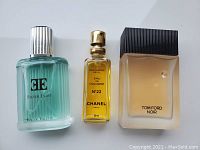 Full view of three men's cologne bottles: Tom Ford Noir, Chanel No 22 Refill, CE Silver Light