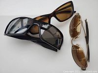 Three pairs of sunglasses shown on white background: tortoiseshell frame with brown lenses, black frame with dark lenses, gold metal frame with brown lenses.