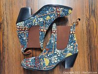 Pair of brand new ladies ankle boots made in Italy with multicolor tweed fabric, brown elastic side panels, and leather stacked block heel on wooden floor.