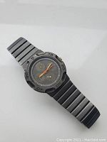 Front view of vintage Bulova watch showing black segmented strap and triple date dial with three subdials and colored hands