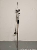 Full view of the heavy duty boom arm part standing upright against white wall, showing adjustable mechanisms and stabilizing rods.
