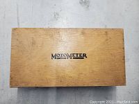 Wooden box lid with MOTOMETER logo printed on it.