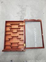 Display case open view showing the interior stepped shelves and the glass door hinged open on the side.