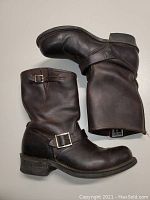 Left and right Frye black biker ankle boots laid separately showing full side profile and sole wear.