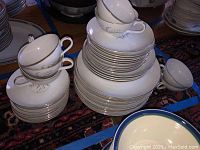 Stacked set of white china cups, plates, and bowls showing overall set condition and sizes.