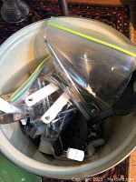 Top view of La Creuset pot containing various kitchen utensils in plastic bags showing nutcrackers, can opener, and spatulas.