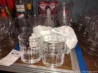 View of four Lenox lowball tumblers with geometric base design and six more assorted clear glasses around