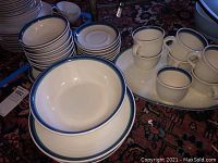 Overall set of Pfaltzgraff dinnerware showing stacked plates, bowls, and cups with blue rim design