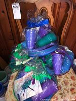 Four plastic picnic kits bundled in clear plastic with purple and green cups and plates visible, also wrapped flatware.