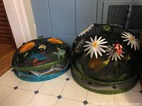 Photo showing two pairs of mesh and nylon platter covers with embroidered floral and insect designs in different sizes.