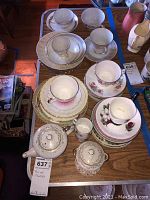 Top-down photo showing layout of teapots, tea cups, saucers, and creamers on a wooden surface