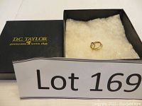 Pair of gold sleeper earrings displayed in a D.C. Taylor branded box with white cushioning inside.