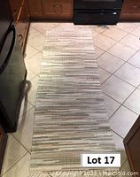 Full view of taupe Mennonite rag rug laid out in a kitchen area showing its rectangular shape and striped woven pattern.